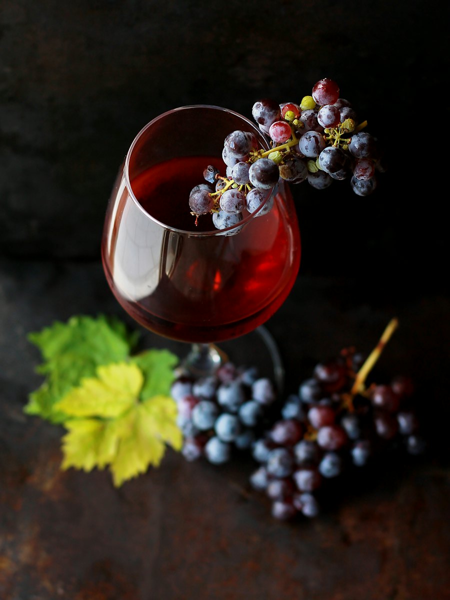 Taça de vinho tinto ao lado de cachos de uva
